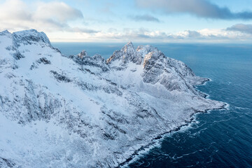 Wall Mural - Snow covered mountain range on coastline in winter, Norway. Senja panoramic aerial view landscape nordic snow cold winter norway ocean cloudy sky snowy mountains. Troms county, Fjordgard 