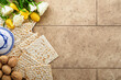Passover celebration concept. Matzah, kosher red wine, walnut and white and yellow roses. Traditional ritual Jewish bread on sand color old tile wall background. Passover food. Pesach Jewish holiday.