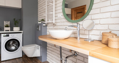 Wall Mural - Modern bathroom interior with ceramic wash basin on wooden counter with faucet and round mirror on white brick wall. Banner.