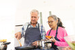 © Wavebreak Media - Happy senior diverse couple cooking dinner in kitchen