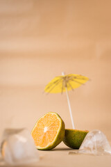 Cut lemon and ice with an umbrella on yellow background