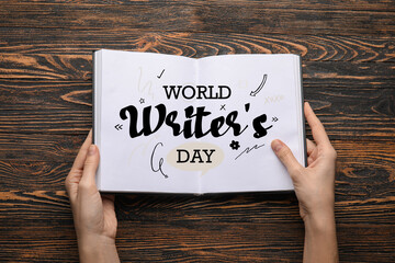 Wall Mural - Banner for World Writer's Day with female hands holding book