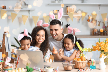 Sticker - Happy interracial family in bunny ears using laptop in kitchen on Easter day