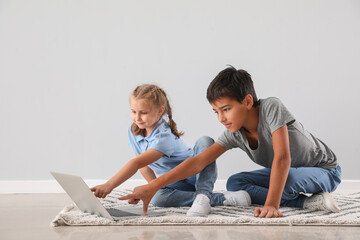 Poster - Little boy and his sister watching cartoons on laptop near light wall