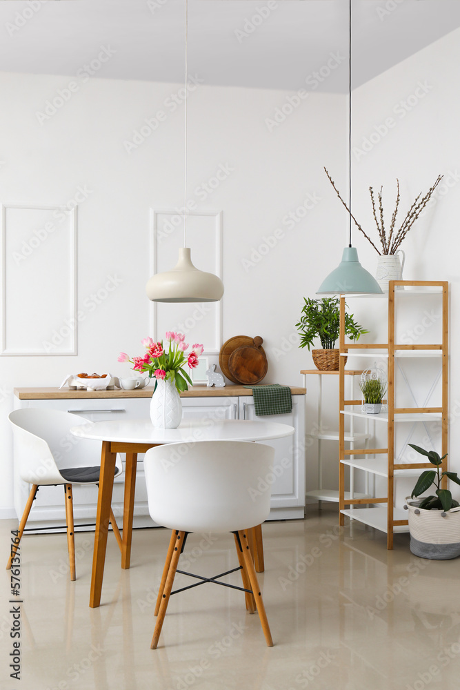 Interior of kitchen decorated for Easter celebration with tulips in vase on dining table