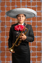 Wall Mural - female mexican mariachi trumpetist woman smiling using a traditional mariachi girl suit on a talavera background. good looking latin hispanic trumpet player musician feminine using a white hat