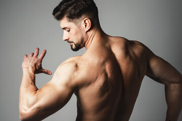 Muscle handsome young man posing over gray background. Perfect body and skin. Studio shot.