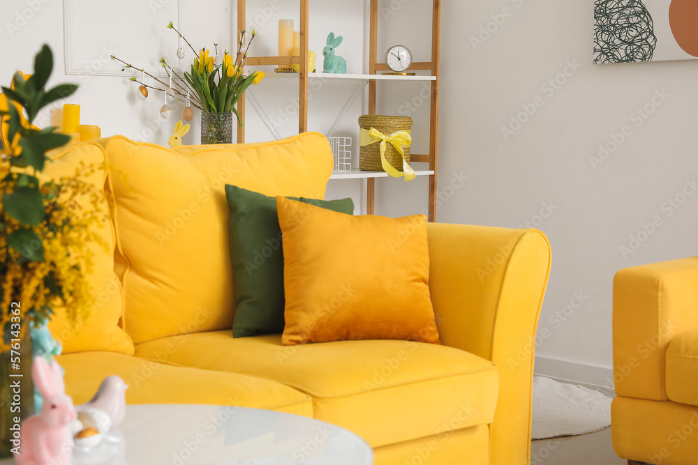 Interior of living room with yellow sofa, tulips and Easter eggs