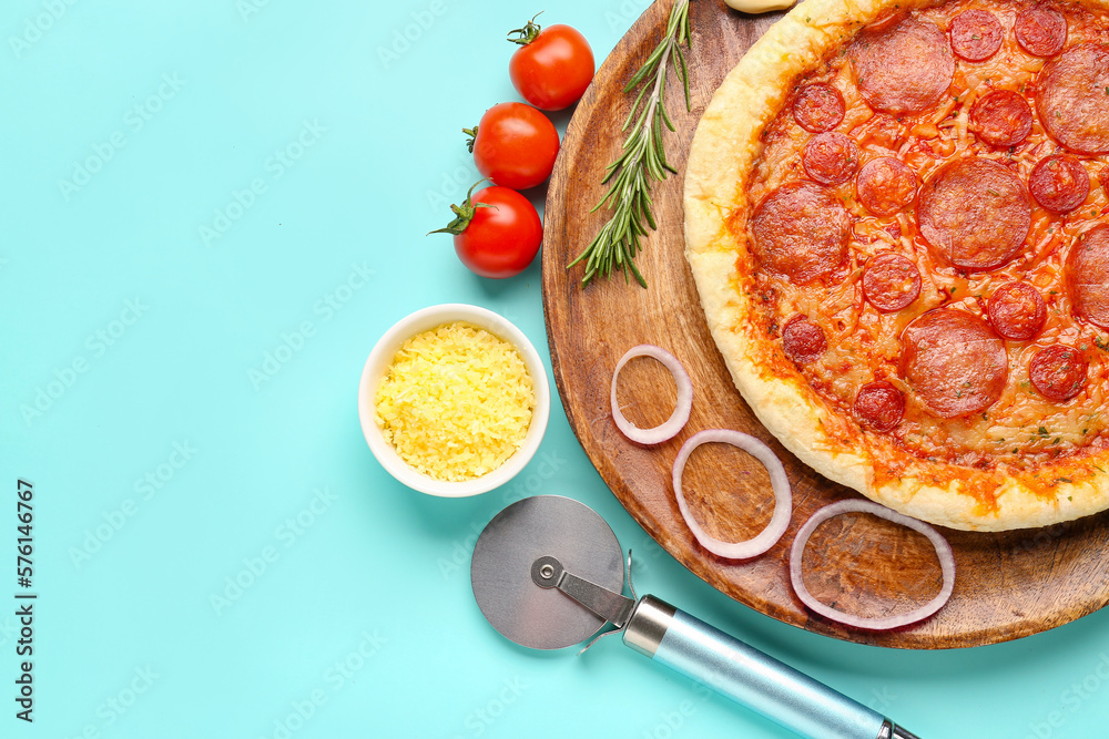 Board with delicious pepperoni pizza and ingredients on turquoise background