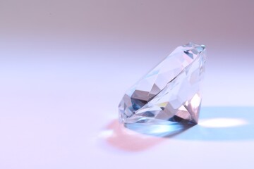 Beautiful dazzling diamond on color background, closeup. Space for text