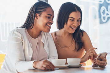 Poster - Women friends, coffee shop and phone with smile, happy and laugh at comic meme on social network. Gen z black woman, smartphone and relax in cafe with blog, funny video or texting app ux on internet