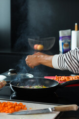 Woman hands adding ingredients in a vegetable stew