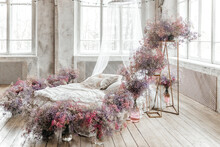 A Bed In A Bright Bedroom In Pastel Colors In Boho Style, The Trending Color Of 2023. The Room Is Decorated With Lilac And Pink Gypsophila Flowers, Vintage Decor In The Room In Retro Loft Style
