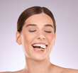 © Rethea B/peopleimages.com - Licorice, happy woman eating and mouth with makeup and cosmetics in an isolated studio. White background, sweet food and candy snack product with hungry female model face with sugar for dessert