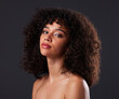 © Rethea B/peopleimages.com - Portrait, makeup and beauty by black woman in studio for glamour, treatment and body care on black background. Face, girl and curly afro model relax with luxury, soft and glowing skin while isolated