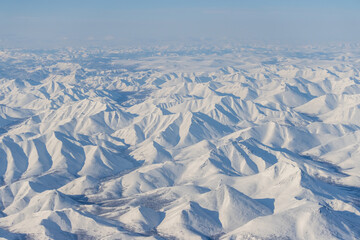 Wall Mural - Aerial view of snow-capped mountains. Winter snowy mountain landscape. Air travel to the far North of Russia. Kolyma Mountains, Magadan Region, Siberia, Russian Far East. Great for the background.