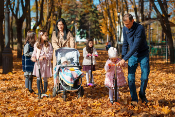 Poster - big family spends time together in autumn city park, children and parents, happy people walk and relax, ride scooters, beautiful nature, bright sunny day and yellow leaves