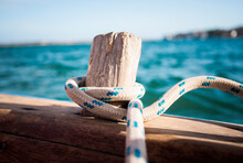 LAMU, INDIAN OCEAN, KENYA, AFRICA. A Rope Wrapped Around An Old Wood Peg On A Wooden Sailboat Adrift In Blue Water.
