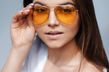 Stylish Female Model With Light Natural Makeup Wearing Trendy Orange Sunglasses