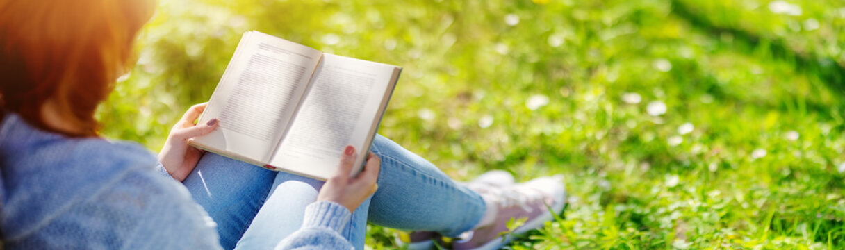 Fototapete - Woman sitting on the blossoming meadow with book in her hands.