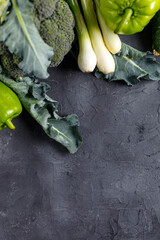 Wall Mural - Border of green raw vegetables on black background. Top view of healthy organic food. Copy space
