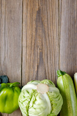 Wall Mural - Border of green raw vegetables on wooden background. Top view of healthy organic food. Copy space