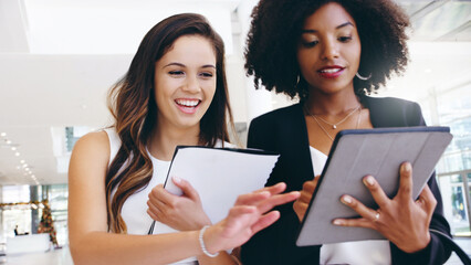 Poster - Its always the right time to make it happen. Shot of two young businesswomen using a digital tablet while walking through a modern office.