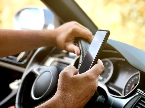 a man who drives is using the mobile. man's hands holding mobile while driving, safety concept and d