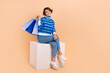 © deagreez - Full body length photo of pretty attractive lady fashionista addicted shopping hold packages sit cube brand promo isolated on beige color background