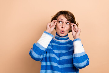 Wall Mural - Photo of excited funky woman dressed striped sweater arms eyewear looking empty space isolated beige color background