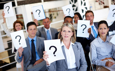 Poster - Stop leaving us in the dark. Shot of a group of businesspeople holding up signs with question marks on them during a work presentation.