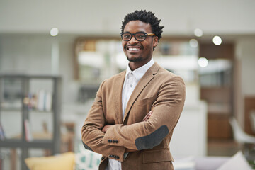 Wall Mural - Looking sharp and feeling great. Cropped portrait of a confident young businessman standing with his arms folded in his office.