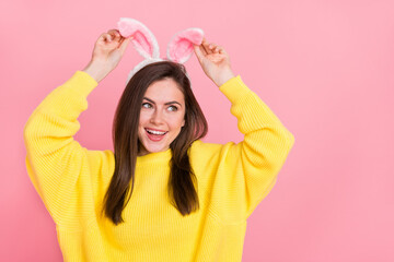 Wall Mural - Photo of young cheerful lady hand touch rabbit ears look empty space isolated over pink color background