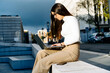 © Jake Jakab - Happy Successful Businesswoman Holding a Takeaway Coffee Cup and smartphone sitting with lattop