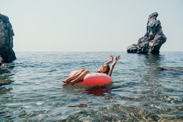 Woman summer sea. Happy woman swimming with inflatable donut on the beach in summer sunny day, surrounded by volcanic mountains. Summer vacation concept.