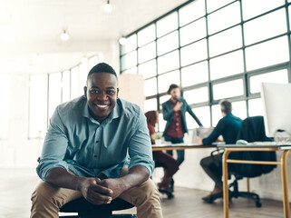 Poster - With confidence comes success. Portrait of a young businessman sitting in a modern office with his colleagues working in the background.