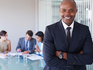 Poster - Climbing the corporate ladder. Portrait of a handsome businessman with his colleagues working in the background.
