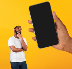 Poster - Interesting Offer. Pensive Black Man Looking At Blank Cellphone In Big Hand