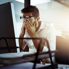 Sticker - The tiredness is setting in. Cropped shot of a young businessman looking stressed while working late in the office.