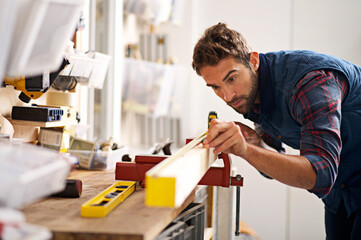 Aufkleber - Down to the very last detail. Shot of a handsome young carpenter measuring a piece of wood.