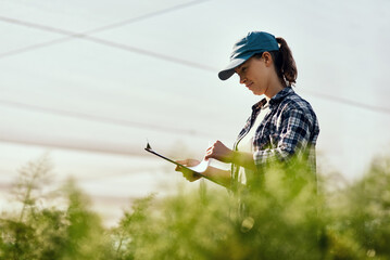 Wall Mural - The greener the better. Cropped shot of an attractive young female farmer looking over paperwork while working on her farm.