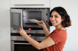 © Prostock-studio - Portrait Of Happy Young Arab Woman Using Microwave In Modern Kitchen