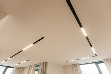 LED strip light and illumination. Also called ribbon light or LED tape to suspended on ceiling in plasterboard in empty living room include down light, white wall. Interior home design and technology