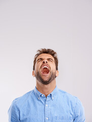 Poster - Theres no hiding his feelings. Studio shot of a handsome young man screaming in anger against a gray background.