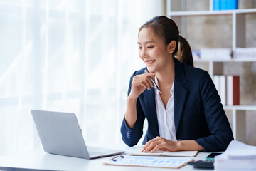 Attractive asian businesswoman sitting working on laptop thinking new idea at office.