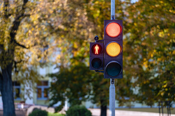 Wall Mural - Red and orange traffic light in semaphore closeup. Bright colored autumn background.