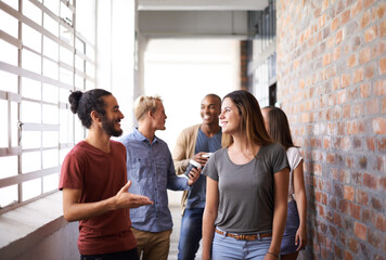 Canvas Print - Catching up on the way to class. Shot of a diverse group of university friends talking in a hallway.