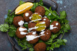Plate of fried falafel balls served with fresh green cilantro and lemon top view on rustic concrete background. Traditional vegan dish of Middle Eastern cuisine