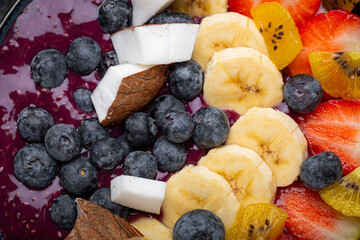 Wall Mural - Healthy summer acai smoothie bowl with chia seeds, fresh banana, strawberry, blueberry, cocos, kiwi top view on rustic concrete background with spoon