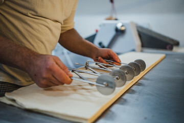 baker man cutting sheet of croissant dough with multiple wheel pastry cutter